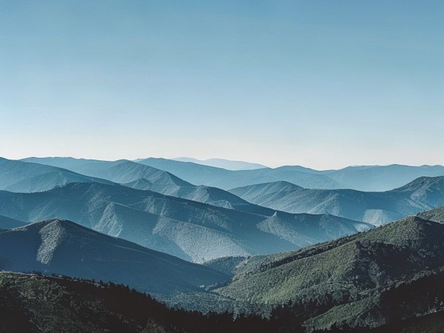 Scenic vista of layered mountains under clear blue sky at midday